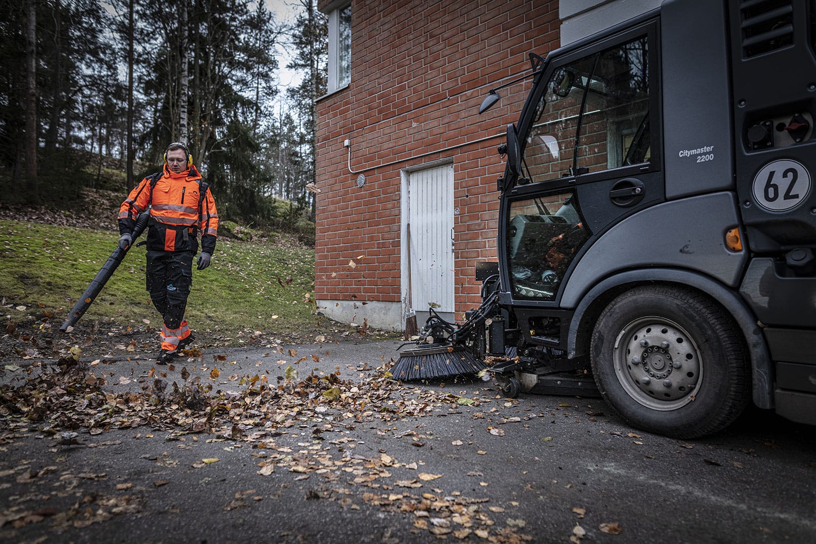 Kiinteistönhoitaja puhaltaa lehtiä puhaltimella