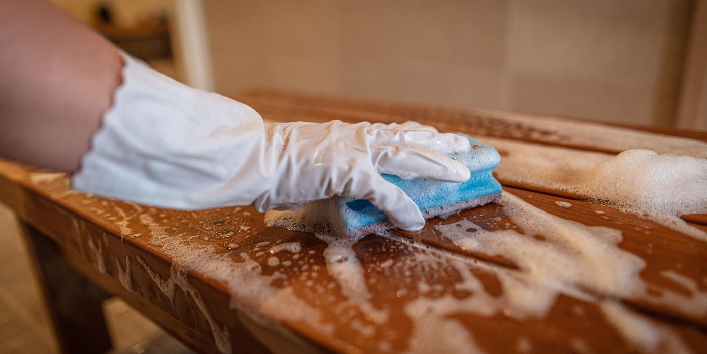 Käsi siivoaa saunan lauteita